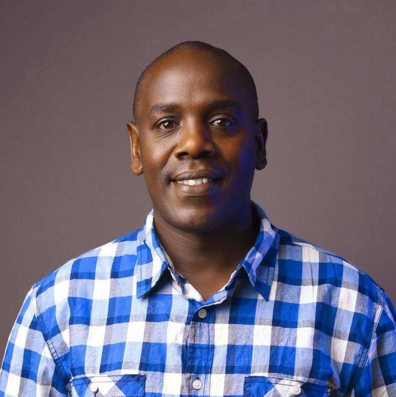 Studio portrait of Enock Change in a blue checked shirt